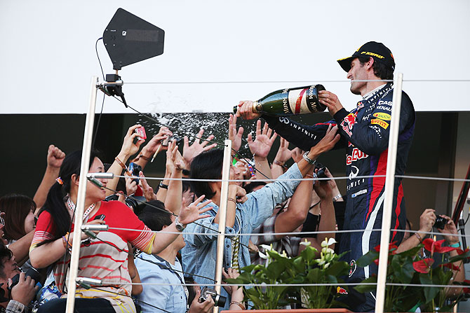 Mark Webber of Red Bull Racing sprays champagne on members of the public in the grandstand after finishing second during the Japanese Formula One Grand Prix at Suzuka Circuit on Sunday