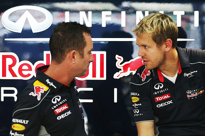 Sebastian Vettel of Germany Red Bull Racing talks with Chief Mechanic Kenny Handkammer in their team garage during previews for the Indian Formula One Grand Prix at Buddh International Circuit on Thursday
