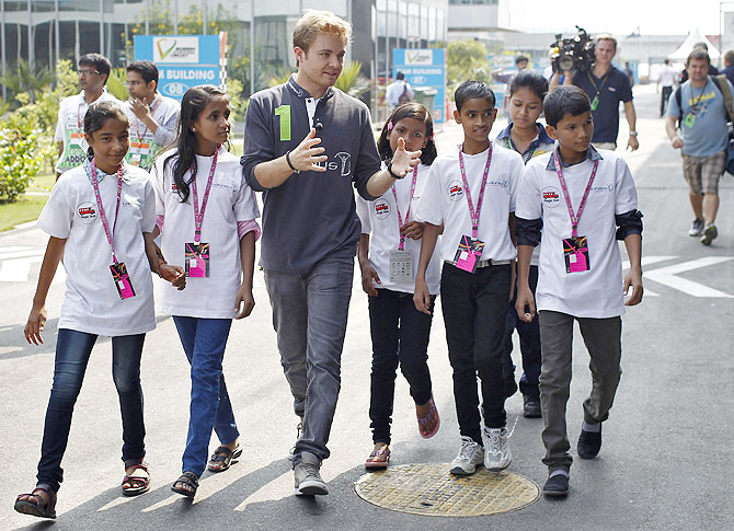 Mercedes Formula One driver Nico Rosberg (centre) of Germany walks with Indian school children in the paddock at the Buddh International Circuit in Greater Noida on Thursday