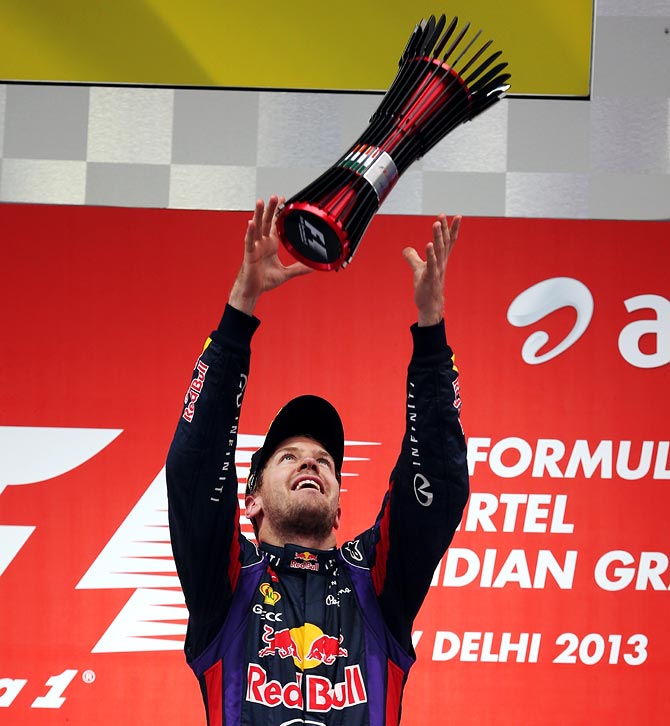 Sebastian Vettel throws his trophy in the air on the podium after winning the Indian F1 Grand Prix