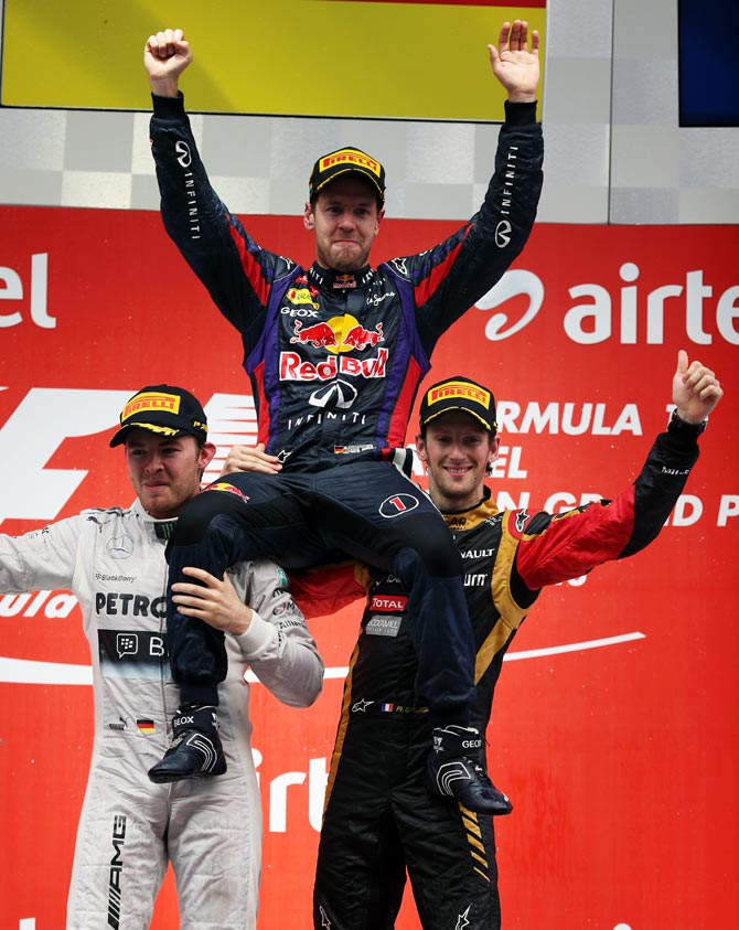 Sebastian Vettel (centre) is lifted up by second placed Nico Rosberg (left) of Mercedes and third placed Romain Grosjean