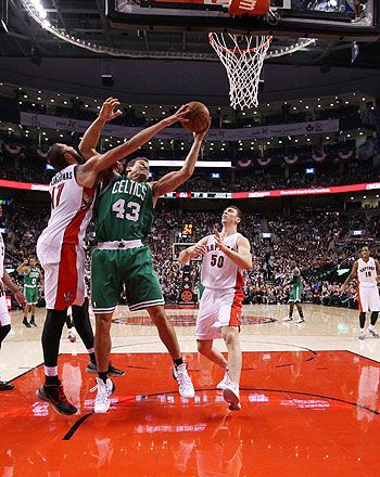 Kris Humphries #43 of the Boston Celtics battles for a rebound with Jonas Valanciunas #17 of the Toronto Raptors as Tyler Hansbrough #50 of the Toronto Raptors looks on