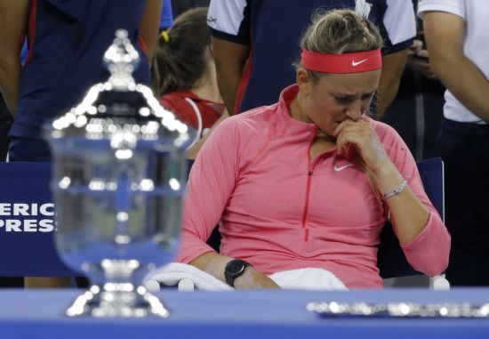 Victoria Azarenka of Belarus wipes her face as she sits by the winner's trophy