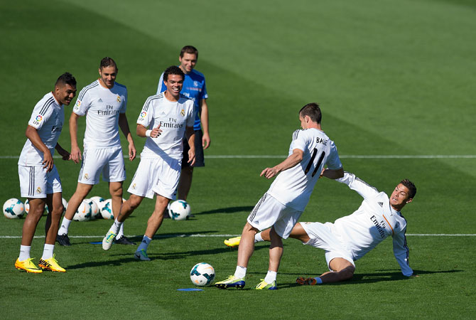 Real Madrid's new signing Gareth Bale is tackled by Cristiano Ronaldo while team mates Jese Rodriguez (left), Karim Benzema (second left), Pepe and assistant coach Zinedine Zidane look on