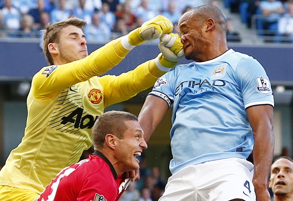 Manchester City's Vincent Kompany (right) gets hit in his face as he is challenged by Manchester United's David de Gea