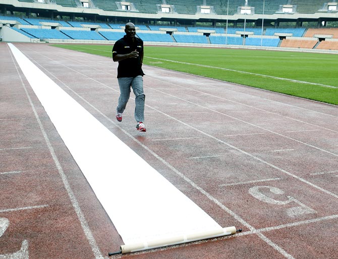 Ben Johnson of Canada runs next to a scroll petition laid out on the track at the Seoul Olympic Stadium