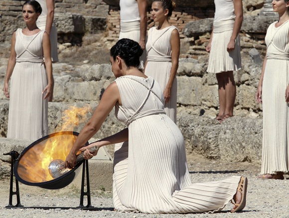 Greek actress Ino Menegaki (front), playing the role of High Priestess, lights a torch from the sun's rays reflected in a   parabolic mirror during a dress rehearsal for the torch lighting ceremony of the Sochi 2014 Winter Olympic Games