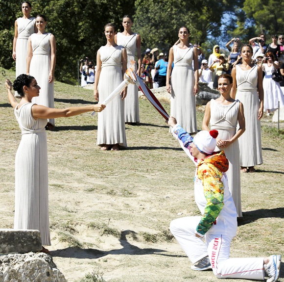 Greek actress Ino Menegaki, playing the role of High Priestess, passes the Olympic flame to Greek skier Yannis Antoniou, the first torchbearer of the torch relay, during a dress rehearsal for the torch lighting ceremony of the Sochi 2014 Winter Olympic Games