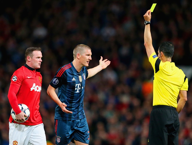 Wayne Rooney of Manchester United looks on as Bastian Schweinsteiger   of Bayern Muenchen receives his first yellow card from Referee Carlos Velasco Carballo