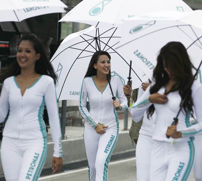 Petronas-sponsored grid girls walk through the pit lane before the third practice session at the Sepang International Circuit April 4, 2009