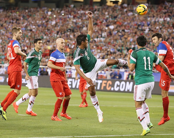 Juan Carlos Valenzuela of Mexico attempts a shot defended by Michael Parkhurst of USA
