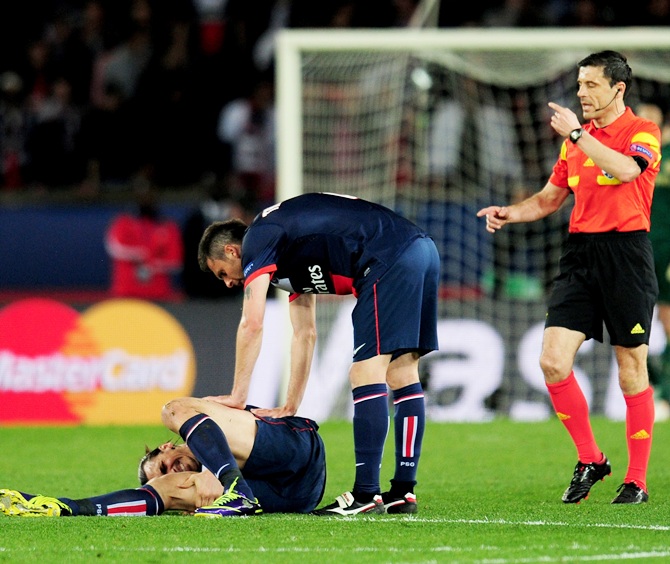 Thiago Motta of PSG checks on teammate Zlatan Ibrahimovic after he goes down injured