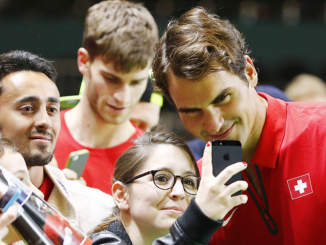 Switzerland's Roger Federer poses with a fan for a selfie after winning his Davis Cup quarter-final tennis match against Andrey Golubev of Kazakhstan on Sunday