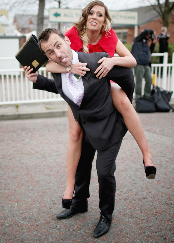 A man carries a girl as racegoers make their way home from Ladies Day