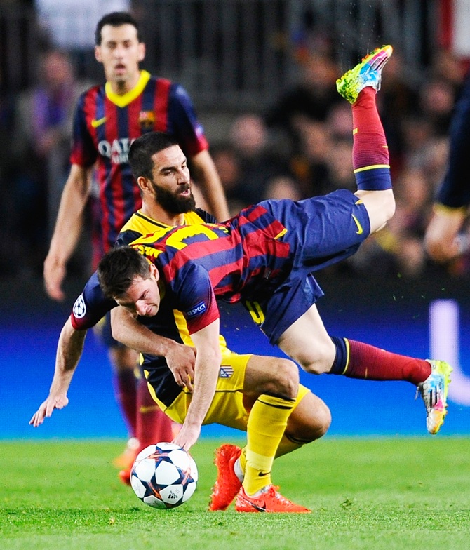 Lionel Messi of Barcelona is challenged by Arda Turan of Club Atletico de Madrid