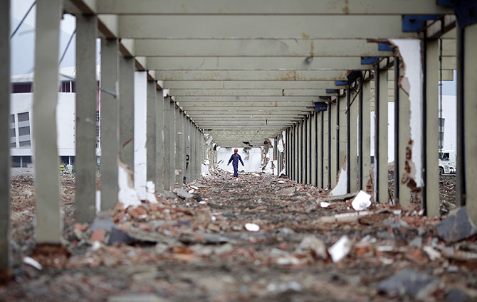 A worker walks at the work site of the Parque Olimpico Rio 2016 (Rio 2016 Olympic Park), which is being constructed over the former Jacarepagua race track