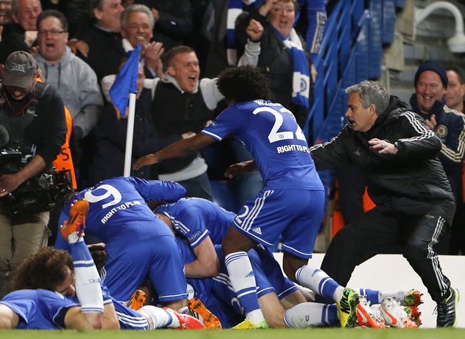 Chelsea's Demba Ba (hidden) celebrates with coach Jose Mourinho, right, and teammates after scoring the second goal