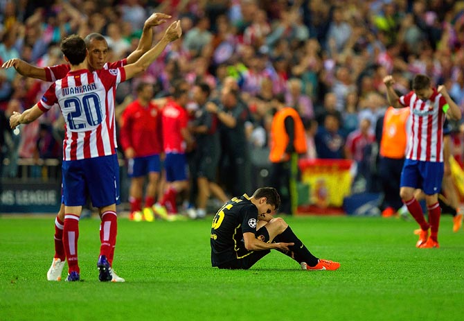 Atletico Madrid players celebrate as Barcelona's Marc Batra sits dejected after the end of the match in Madrid.