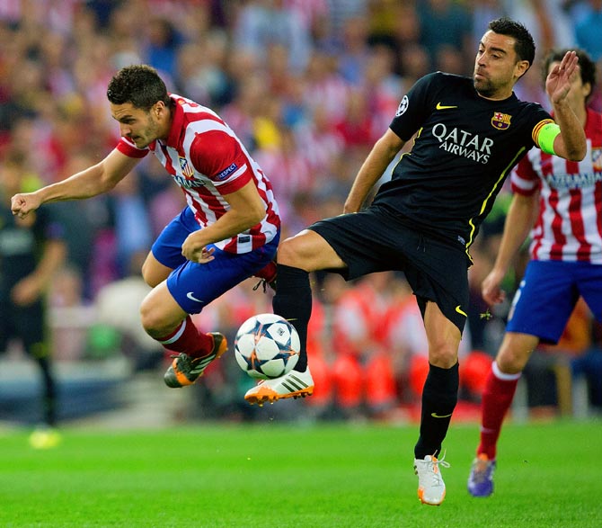 Barcelona's Xavi tackles Koke of Atletico Madrid