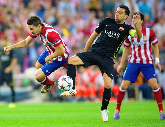 Xavi of Barcelona tackles Koke of Club Atletico de Madrid