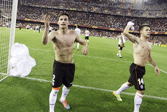 Valencia's Pablo Piatti (left) and Juan Bernat throw their shirts to supporters as they celebrate victory over FC Basel after their Europa League quarter-final second leg match at the Mestalla stadium in Valencia, on Thursday