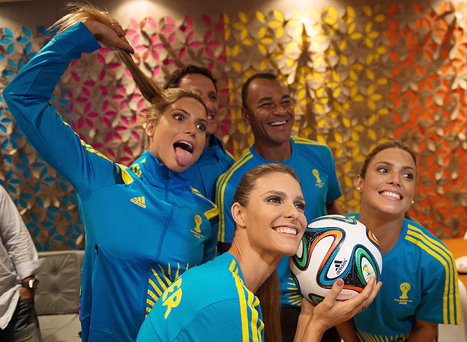 Brazilian former world champions players Juliano Belleti (blurred in background) and former Brazil football captain Cafu (behind right), synchronized swimming athletes Bia (left) and Branca Feres (right) and Brazilian TV presenter and model Fernanda Lima (2nd from left) pose for photo after Volunteers Uniform launch of the 2014 FIFA World Cup during Fashion Rio Summer 2014/2015 at Marina da Gloria in Rio de Janeiro on Thursday