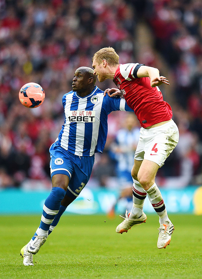 Marc-Antoine Fortune of Wigan Athletic and Per Mertesacker of Arsenal battle for the ball on Saturday