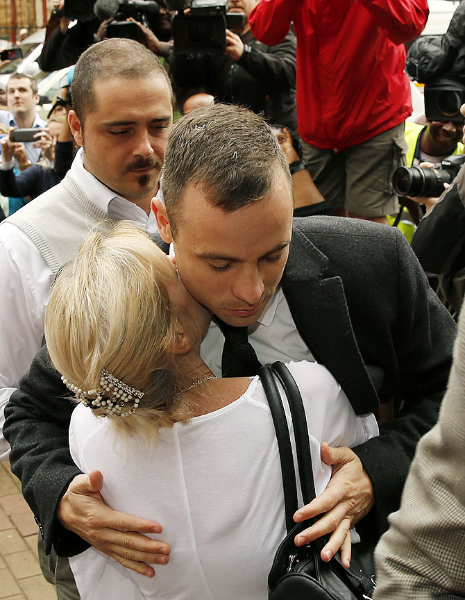 Olympic and Paralympic track star Oscar Pistorius (right) is hugged by a supporter as he arrives ahead of his trial for the murder of his girlfriend Reeva Steenkamp at the North Gauteng High Court in Pretoria on Monday