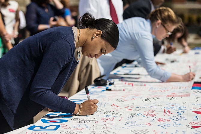 A woman writes a tribute on a memorial before a flag raising ceremony at Boston Medical Center to commemorate the one year anniversary of the Boston marathon bombings on Tuesday