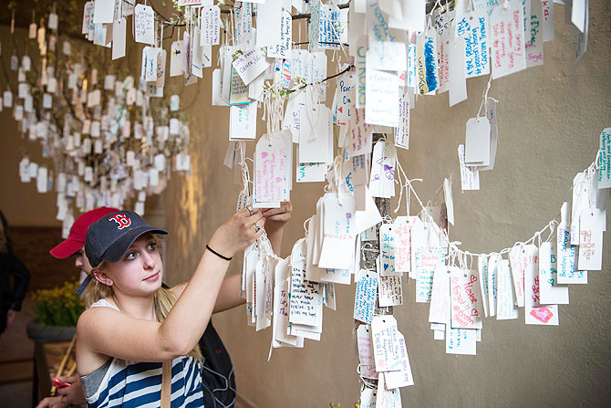 Kathryn Shea, from Rochester, New York, hangs a hand-written message she wrote on a tree hung with messages inside a display titled, 'Dear Boston: Messages from the Marathon Memorial' in the Boston Public Library to commemorate the 2013 Boston Maraton bombings, on Tuesday