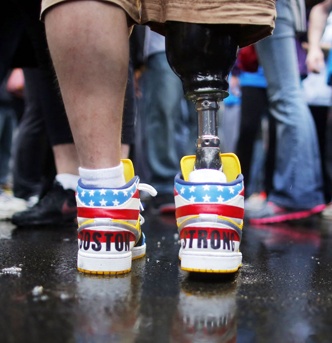 The shoes of 2013 Boston Marathon bombing survivor J.P. Norden read 'Boston Strong' as he stands at the finish line on the one-year anniversary of the bombings in Boston, Massachusetts on Tuesday. J.P. and his brother Paul, also a bombing survivor, took part in the final portion of the 'Legs for Life Relay', joining family members and friends who walked the entire Marathon route to raise money for children needing prosthetic limbs.