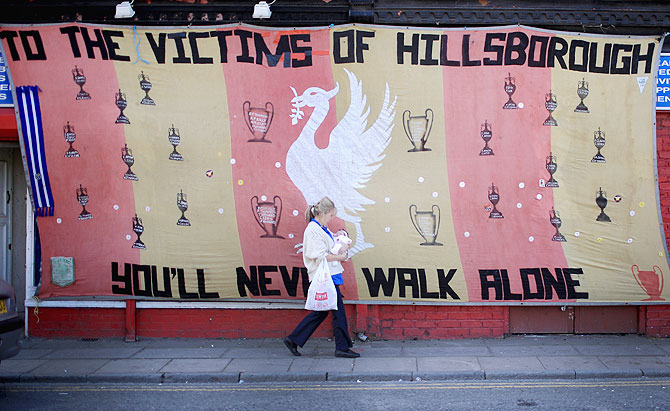  woman walks past a Hillsborough tribute banner as fans arrive in Anfield for a memorial service marking the 25th anniversary of the Hillsborough Disaster at Anfield stadium in Liverpool on April 16, 2014