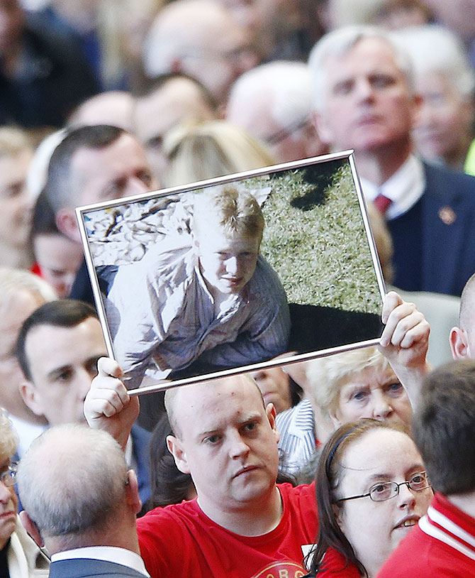 A man holds up a picture of a victim during a memorial service to mark the 25th anniversary of the Hillsborough disaster at Anfield on Tuesday