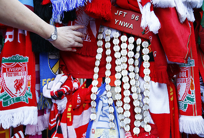 A fan looks at scarves placed as tributes on the Shankly gates before a memorial service to mark the 25th anniversary of the Hillsborough disaster at Anfield on Tuesday