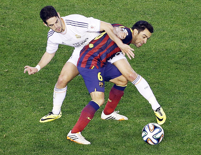 Barcelona's Xavi Hernandez (right) gets entangled with Real Madrid's Isco as they vie for possession on Wednesday