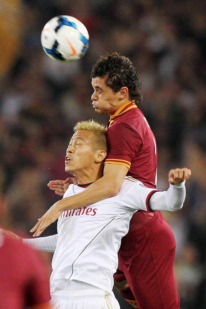 Keisuke Honda (left) of AC Milan competes for the ball with Dodo of AS Roma during the Serie A match at Stadio Olimpico in Rome, Italy on Friday