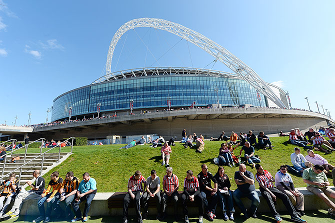 Football fans sit on the grass outside Wembley stadium