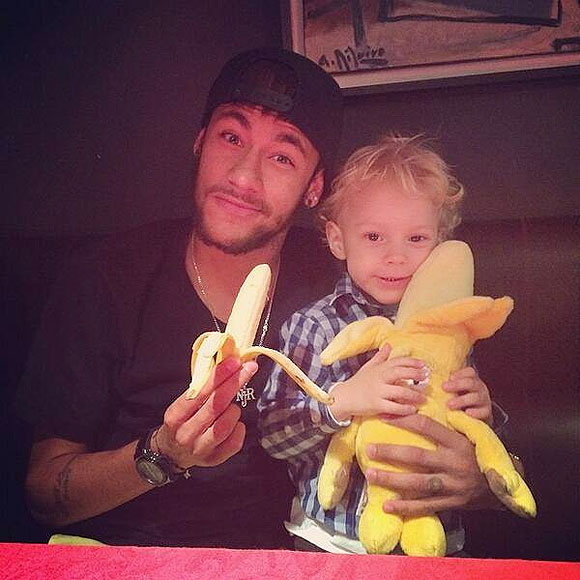 Neymar and his two-year-old son David Lucca da Silva Santos eat a banana as they pose on Tuesday