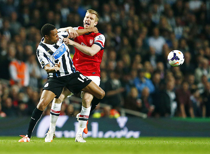 Arsenal's Per Mertesacker (right) is challenged by Newcastle United's Loic Remy during their English Premier League match  on Monday
