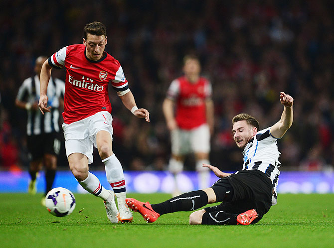 Paul Dummett of Newcastle United tackles Mesut Ozil of Arsenal during their English Premier League match at Emirates Stadium on Monday