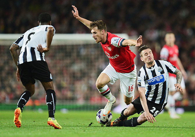 Aaron Ramsey of Arsenal takes on Vurnon Anita (left) and Mathieu Debuchy of Newcastle United (right) during their English Premier League match at Emirates Stadium on Monday