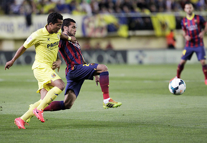 Barcelona's Dani Alves and Villarreal's Giovani Dos Santos vie for possession during their La Liga match at the Madrigal stadium in Villarreal on Sunday
