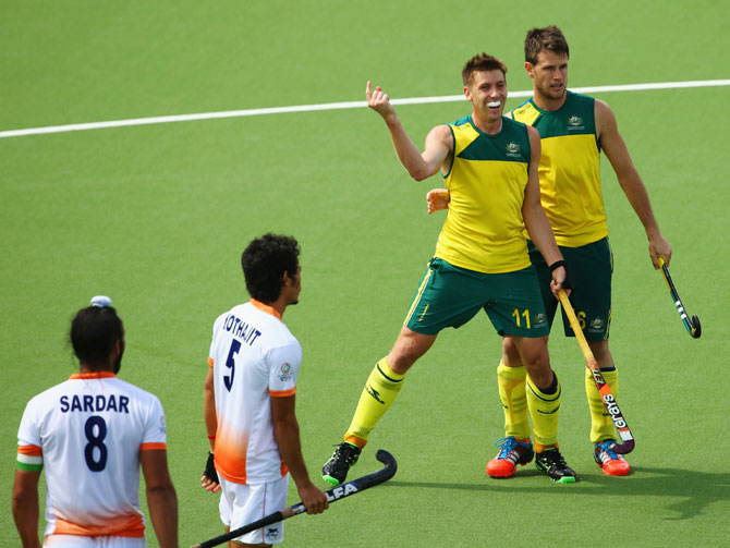 Kothajit Khadangbam (5) and Sardar Singh (8) of India look on as Eddie Ockenden of Australia (11) celebrates with Matt Gohdes (16) as he scores their fourth goal in the gold medal match in Glasgow