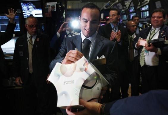 US soccer player Landon Donovan autographs a ball on the floor of the New York Stock Exchange