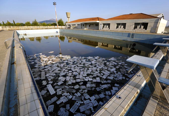 Garbage floats in a deserted swimming pool at the Olympic Village in Thrakomakedones, north of Athens