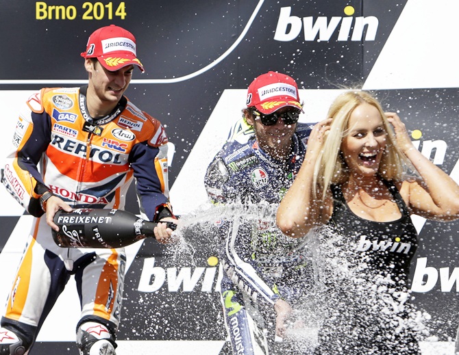 Winner Honda MotoGP rider Dani Pedrosa, left, of Spain and third-placed Yamaha MotoGP rider Valentino Rossi of Italy spray champagne on a hostess after the Czech Grand Prix in Brno