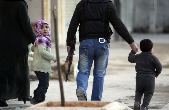A girl wearing a pink scarf flees with her family from shelling in the al-Masir area in Aleppo