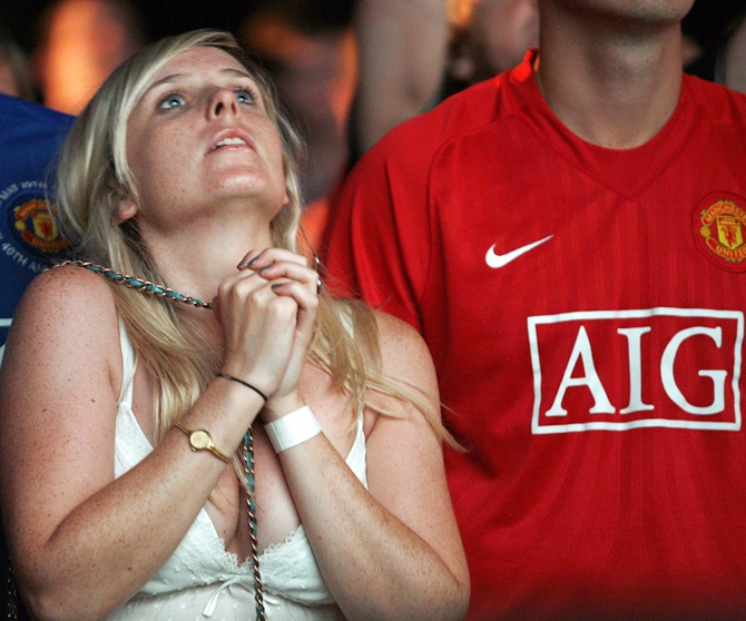 A Manchester United supporter reacts as she watches