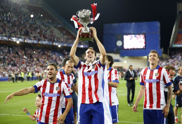 Atletico Madrid's Diego Godin (C), Koke (L) and Mario Mandzukic celebrate with the trophy after they won the Spanish Super Cup against Real Madrid 