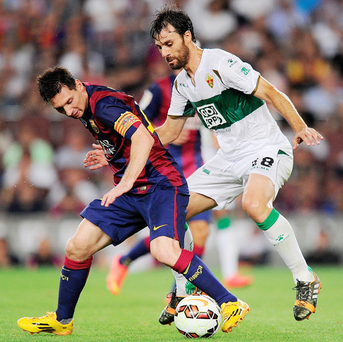 Lionel Messi of FC Barcelona shields the ball from Sergio Pelegrin of Elche FC during the La Liga match on Sunday